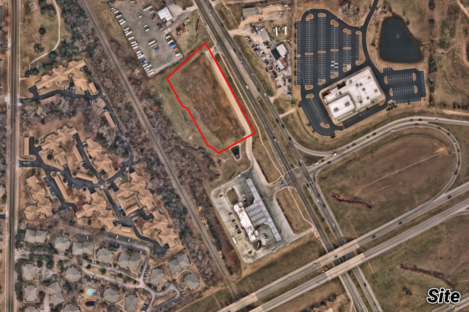 Aerial of the vacant Whataburger parcel outlined in red along a highway, near apartment complexes and an existing convenience store.