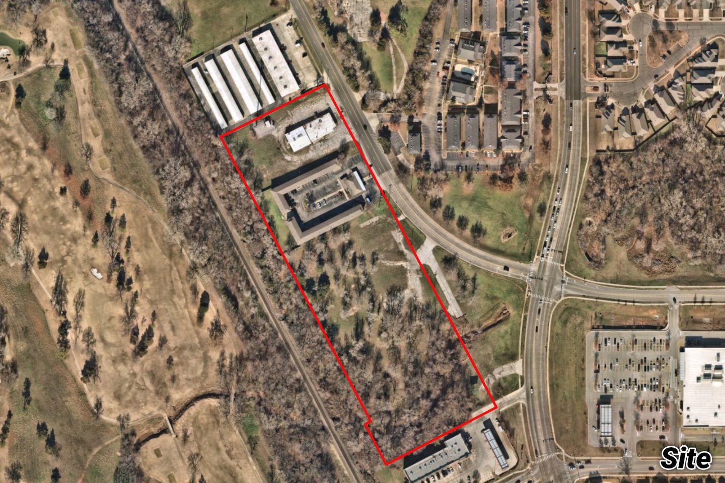 Aerial of the narrow tract outlined in red along the road, holding the low OU Motel buildings, between a golf course and apartments.